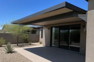 Cantilever metal shade structure over a stone patio with agave plants in a Phoenix, AZ backyard.