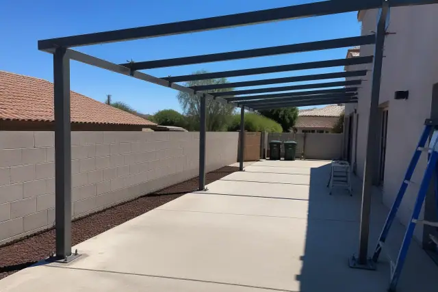 Carport installation progress with steel support columns and framing on a concrete driveway in Peoria, AZ.