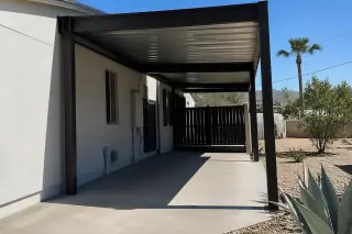 Metal carport structure over a concrete parking slab with agave plants in a Phoenix, AZ backyard.