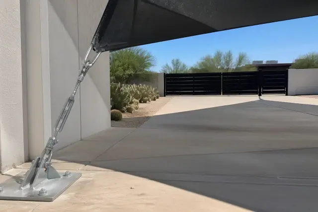 Heavy-duty shade sail anchor plate installed on a concrete parking pad at a property in Phoenix, AZ.