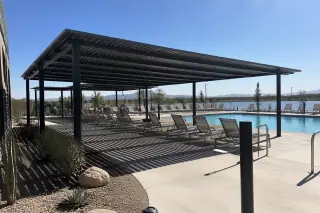 Metal-frame shade structure over a pool deck with desert succulents in a Phoenix, AZ backyard.