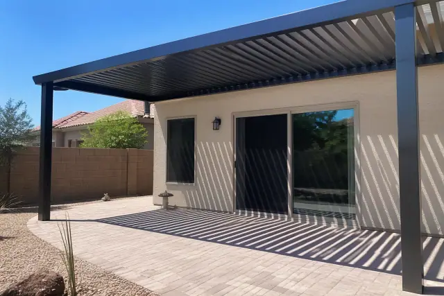 Custom patio cover installation over a paved backyard area with desert landscaping in Phoenix, AZ.