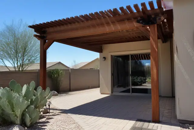 Custom wooden pergola over a stone patio with prickly pear cactus in a Phoenix, AZ backyard.