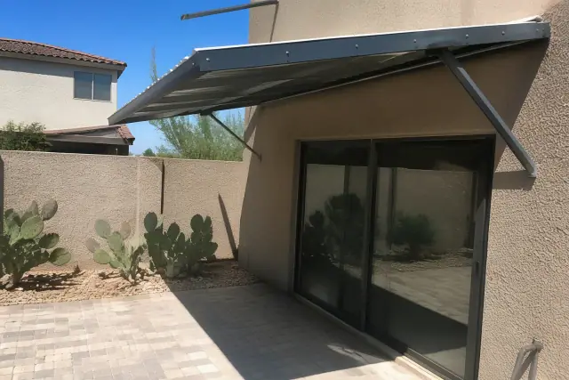Fixed aluminum awnings installed above a sliding glass door at a stone patio in Phoenix, AZ.
