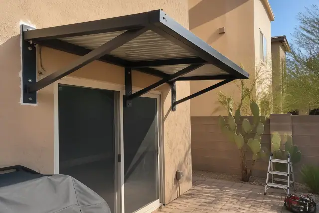 Fixed metal awning installed over a residential patio door with cactus landscaping in Phoenix, AZ.