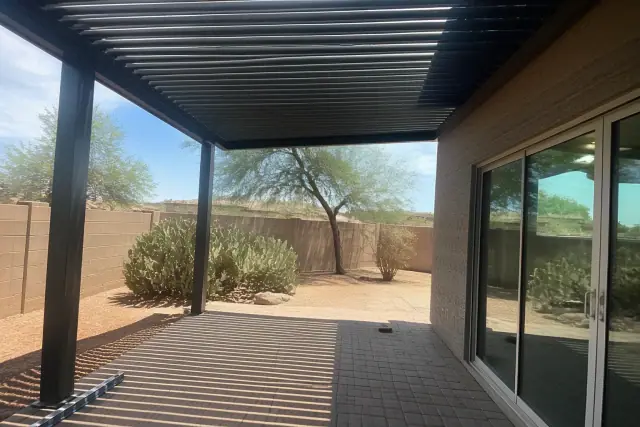 Louvered roof installation over a paved patio in Queen Creek, AZ with aluminum slats casting shadows.