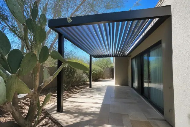 Louvered roof system installed over a paved patio in Phoenix, AZ, next to a sliding glass door.
