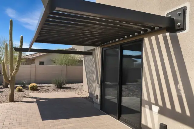 Metal awning installation with a bolted mounting bracket above a patio door in a Scottsdale, AZ backyard.
