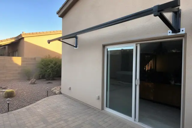 Metal awning support brackets installed on a stucco wall at a residential patio in Surprise, AZ.