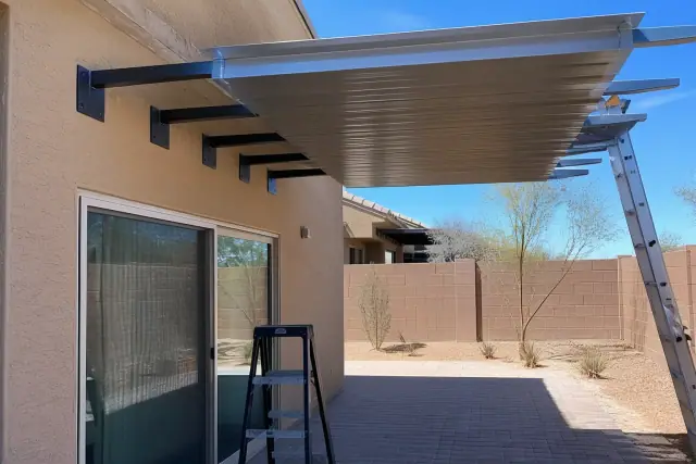 Metal awning being installed over a backyard patio door in Queen Creek, AZ.