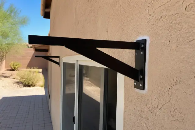 Metal support bracket installed on a stucco wall above a sliding glass door at a jobsite in Phoenix, AZ.
