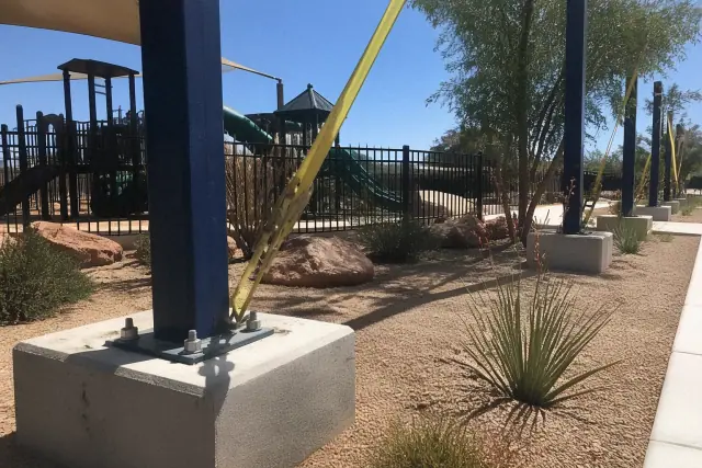 Steel mounting plates and tensioning straps on a playground shade structure installation in Phoenix, AZ.