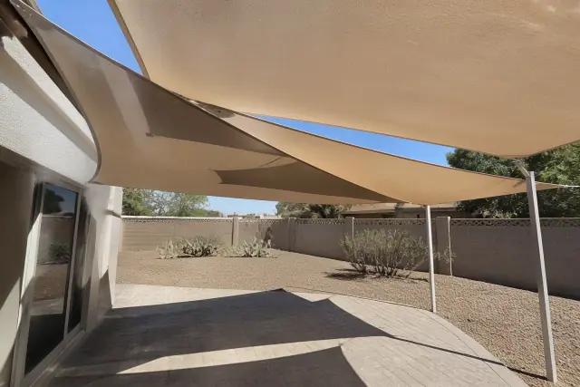 Overlapping multi-sail shade system installed over a stone patio in Phoenix, AZ with cacti in the background.