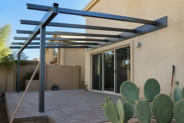 Aluminum patio cover installation in progress over a stone backyard patio in Phoenix, AZ.