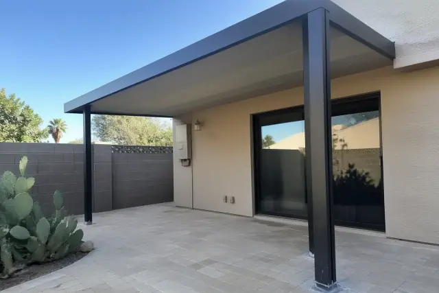 Steel patio cover installed over a paved backyard patio with prickly pear cactus in Tempe, AZ.
