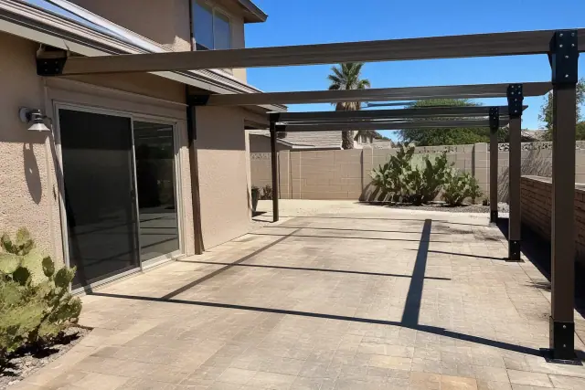 Steel patio cover beams and mounting brackets being installed on a stone patio in a backyard in Glendale, AZ.
