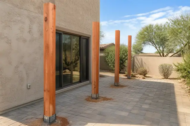 Cedar pergola support posts being installed on a paved patio in Peoria, AZ.
