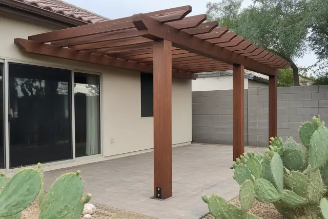 A pergola being installed with timber posts anchored to stone pavers in Mesa, AZ.