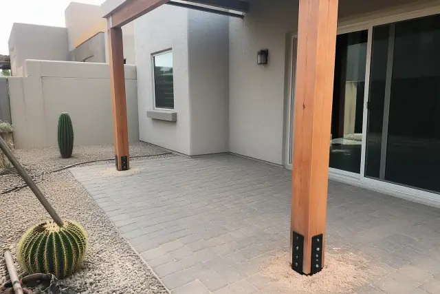 New cedar pergola support posts installed on a stone patio in a residential backyard in Tempe, AZ.