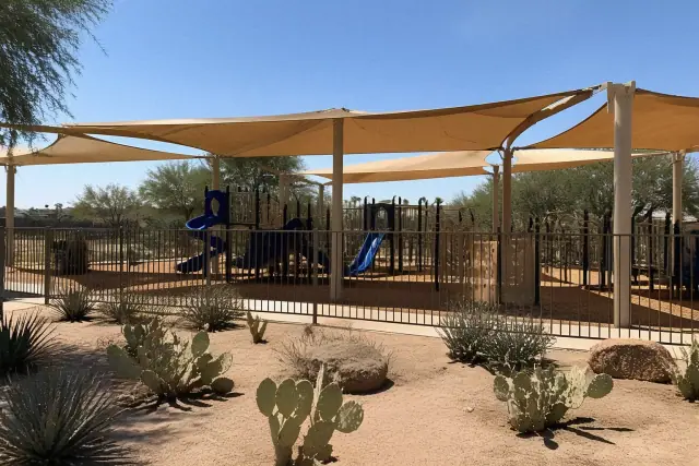 Playground shade structures over climbing equipment at a public park in Phoenix, AZ, with desert landscaping.