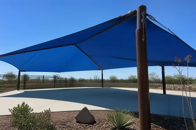 Playground shade structures with steel mounting bolts and fabric ratchets over a xeriscaped park in Mesa, AZ.