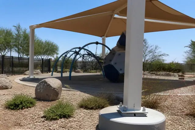 Playground shade structures installed over climbing equipment in a sunny park in Tempe, AZ.