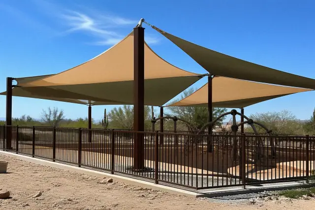 Steel shade structures installed over a playground in Goodyear, AZ with fabric canopies and concrete footings.