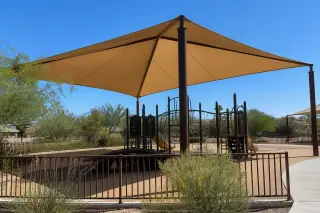 Fabric shade structure over a public playground with desert landscaping in Phoenix, AZ.