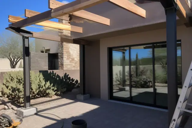 Steel shade structure frame with timber beams on a paved patio in Gilbert, AZ.
