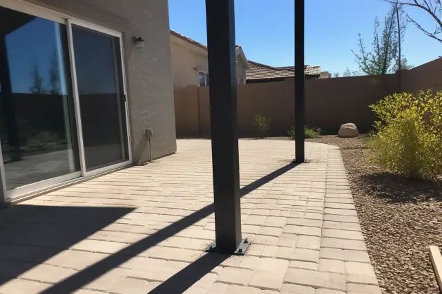 Steel shade structure support posts anchored into stone patio pavers at a residential backyard in Surprise, AZ.