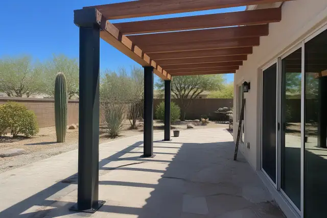 Custom steel and wood shade structure framing installed on a residential stone patio in Scottsdale, AZ.