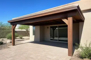 New wood-framed ramada structure casting shade over a stone patio in a Phoenix, AZ backyard.