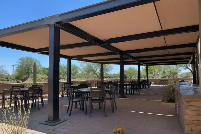 Steel patio cover with fabric shade panels over an outdoor dining terrace in Phoenix, AZ.