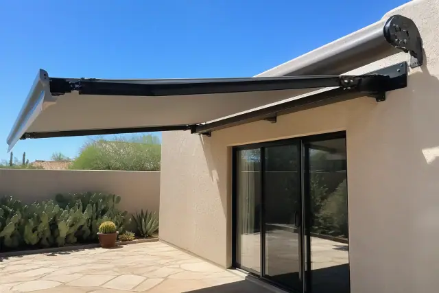 Retractable motorized awning with fabric tension bar and metal brackets on a stucco wall in a Phoenix, AZ backyard.