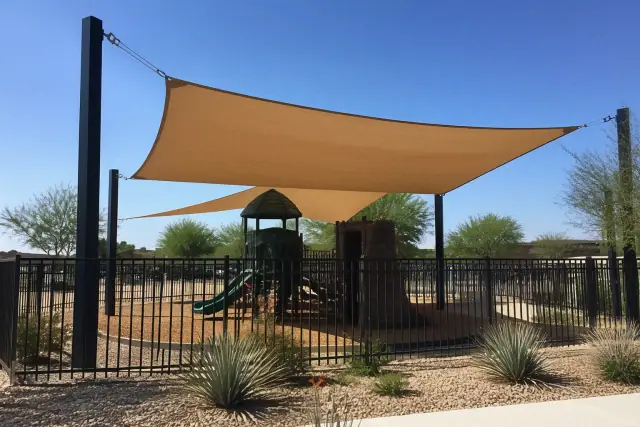 Newly installed shade canopy over a playground with steel support posts and tension cables in Phoenix, AZ.