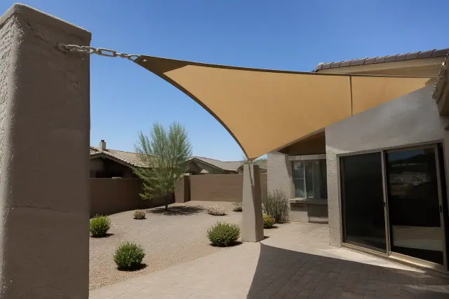 Shade sail installation over a paved stone patio in a residential backyard in Queen Creek, AZ.
