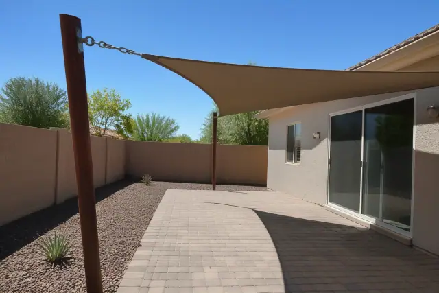 Triangular shade sail installed over a paved patio in a residential backyard in Surprise, AZ.