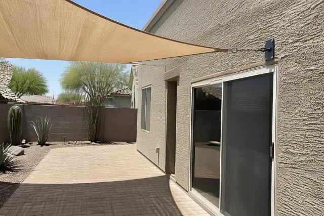 Shade sail installation on a residential patio in Chandler, AZ, showing tensioned fabric attached to a wall bracket.
