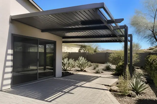 Standing-seam and louvered patio roof covers over a paved backyard in Phoenix, AZ, surrounded by desert xeriscaping.