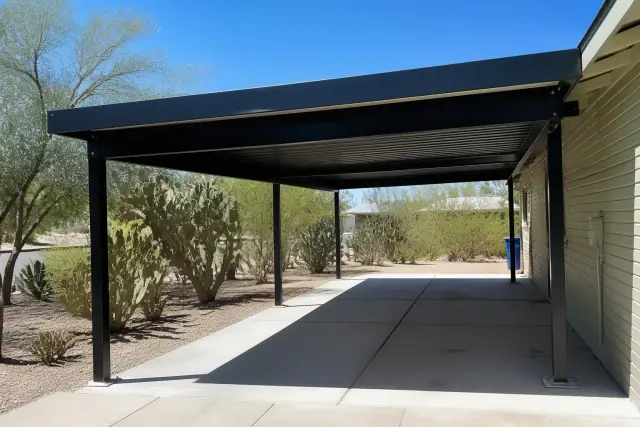 Newly installed steel carport with bolted base plates on a concrete slab in Phoenix, AZ with desert landscaping.