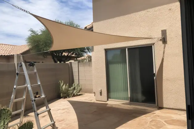 Triangular patio shade sail installed over a paved backyard area with cactus landscaping in Phoenix, AZ.