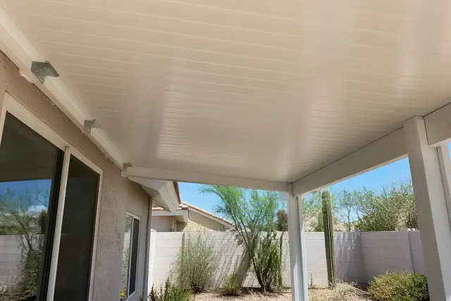 White vinyl patio cover installation with steel mounting brackets in a Phoenix, AZ backyard.