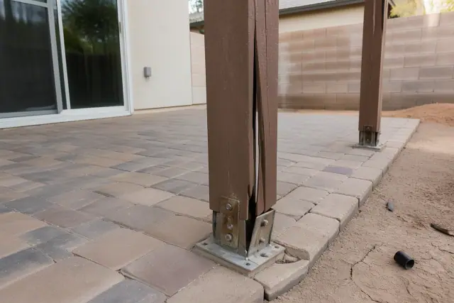 Wind-stressed posts and anchor hardware on a residential patio with cracked desert soil in Phoenix, AZ.