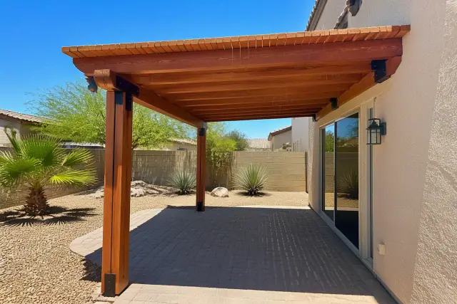 Cedar wood pergola installed over a paved patio in a Phoenix, AZ backyard with xeriscaped desert landscaping.