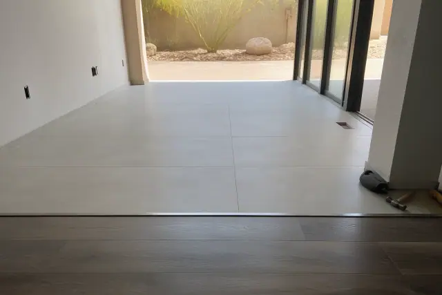 Completed 24x48 porcelain tile installation with a transition strip to wood flooring in a Phoenix, AZ home.
