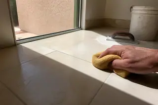 Contractor wiping excess mortar from new stone bathroom floor tiles in a Phoenix, AZ home.