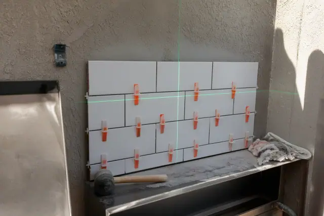Laser level beam aligned on a kitchen backsplash installation at a job site in Phoenix, AZ.