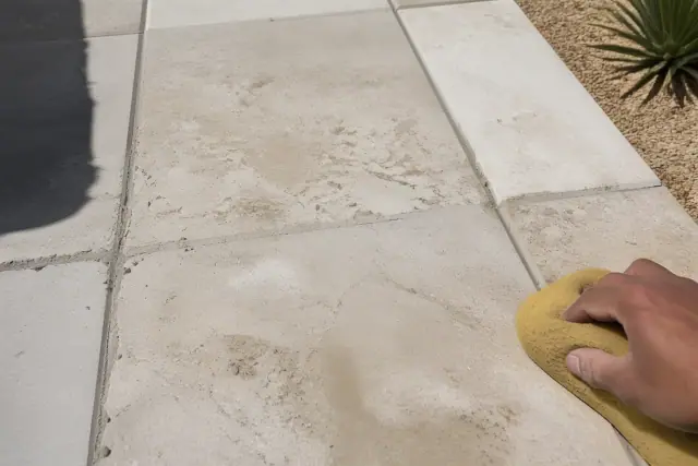 Technician wiping mortar from grout lines between newly installed stone tiles in Gilbert, AZ.