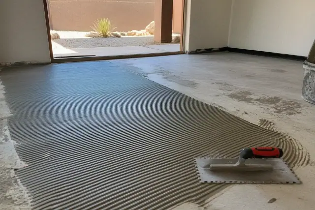 Contractor spreading adhesive on a floor for tile installation at a jobsite in Phoenix, AZ.
