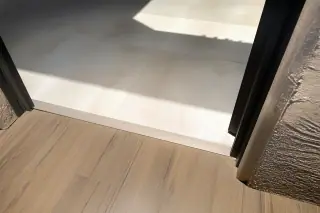 Metal transition strip connecting new tile and wood flooring in a Phoenix, AZ home.